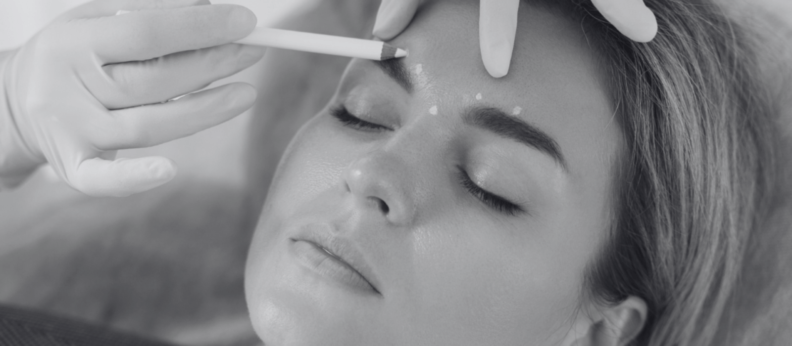 Doctor making marks on client's face before filler injections in aesthetics medical clinic